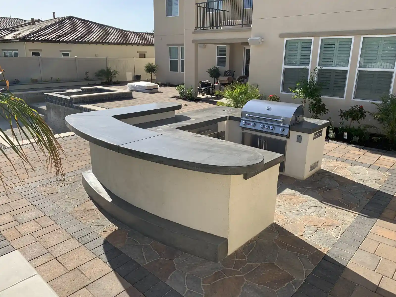 Curved outdoor kitchen island with grill on a stamped patio by Panjia Outdoors
